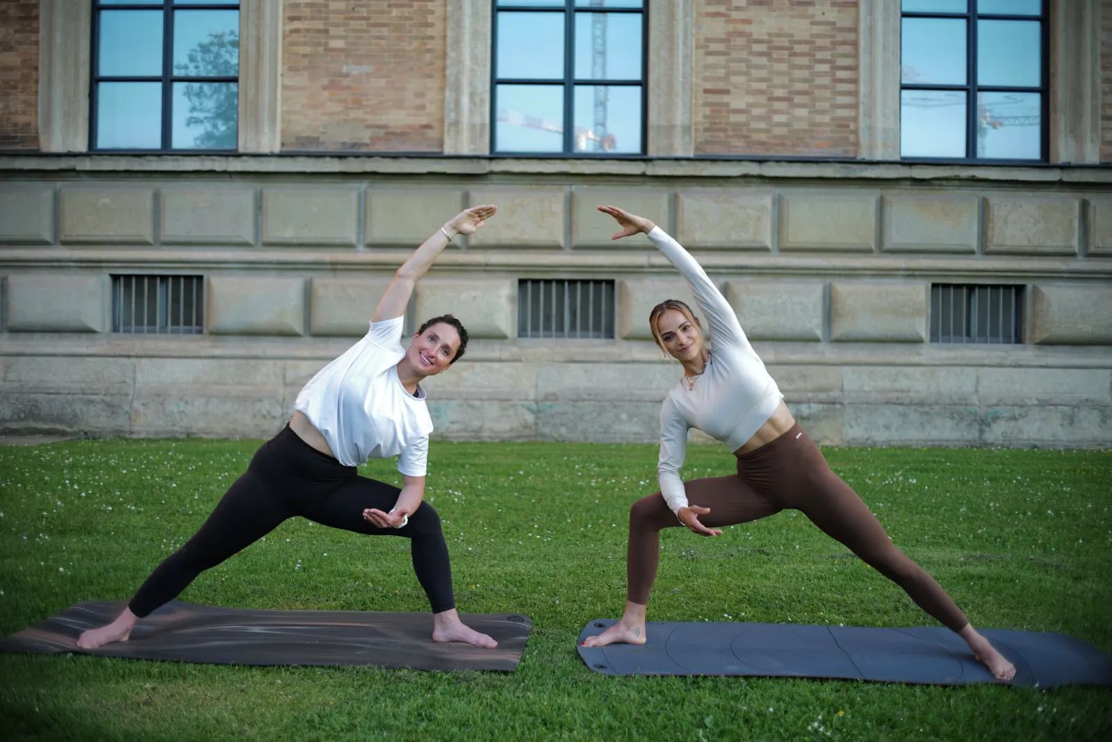Laura und eine Klientin bei einer Yoga-Dehnung im Park.