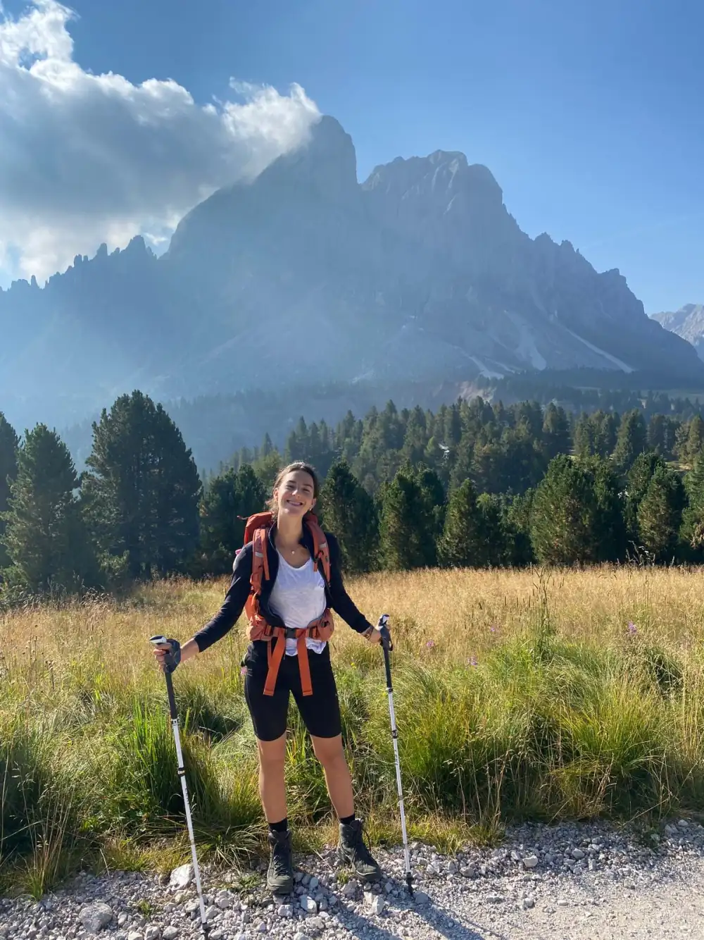 Chrissi on a hike in the Dolomites, laughing with her backpack