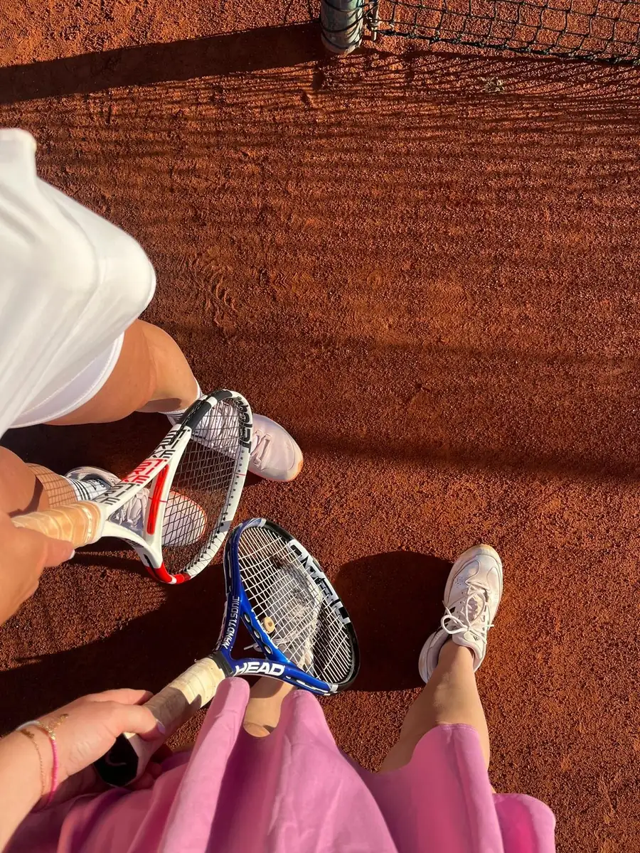 Tennis-Schläger und Schuhe auf einem Sandplatz
